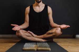 Adult male practicing meditation indoors with a focus on a nails board, promoting mindfulness and calmness.