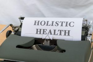 Close-up of a vintage typewriter with 'Holistic Health' typed on paper, symbolizing wellness.