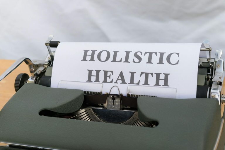 Close-up of a vintage typewriter with 'Holistic Health' typed on paper, symbolizing wellness.