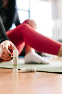 Focused shot of a woman applying CBD balm during a yoga session indoors.