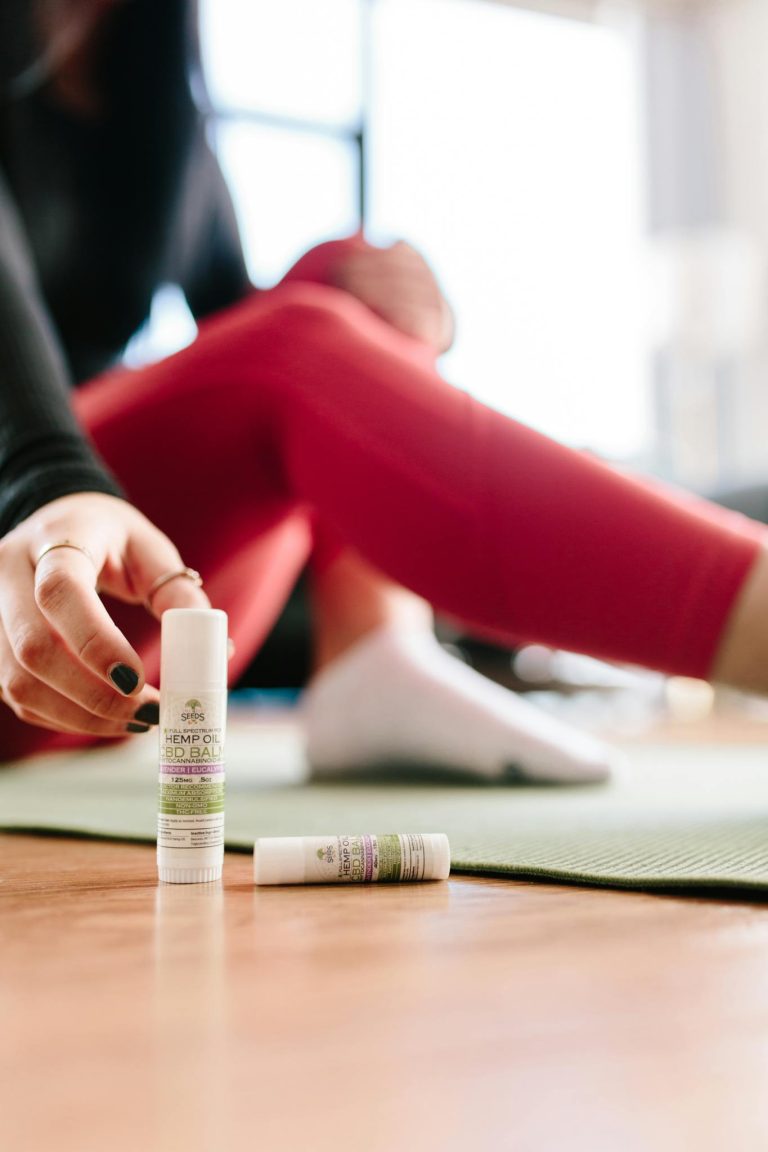 Focused shot of a woman applying CBD balm during a yoga session indoors.